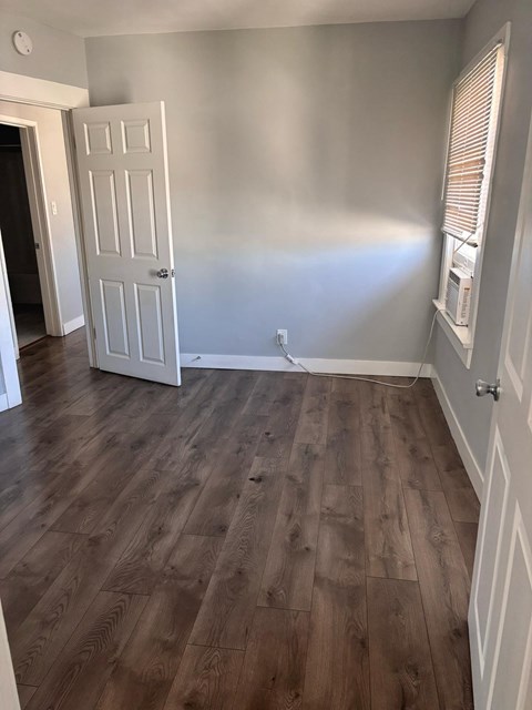 A room with a white door and wooden flooring.