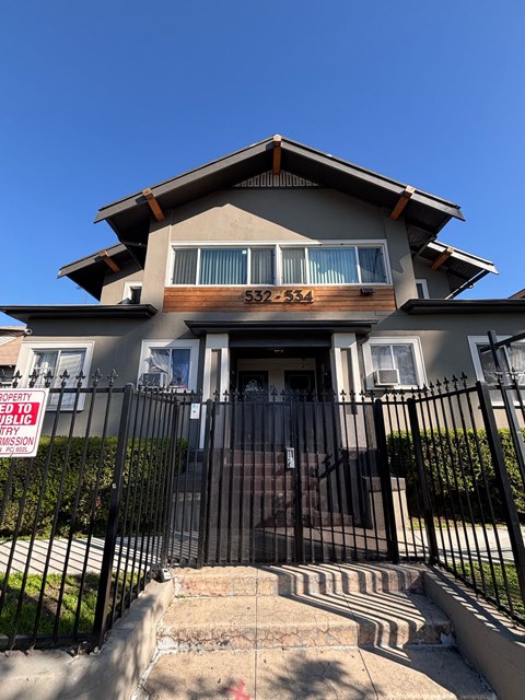 A house with a black fence and a sign that says "For Sale".