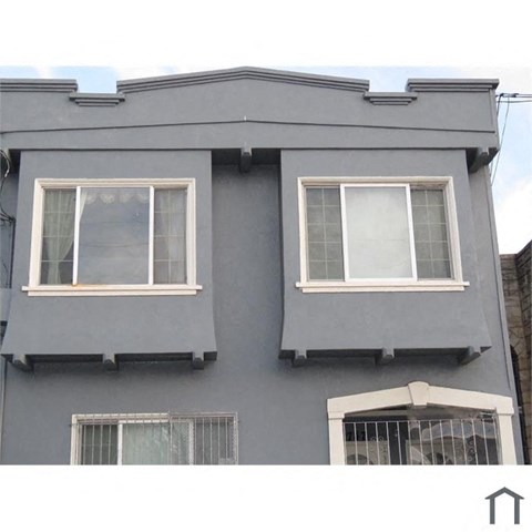 A grey building with two windows and a balcony.
