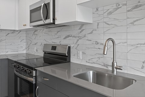 A modern kitchen with a stainless steel sink and a microwave above the stove.