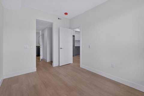 A room with white walls and wooden flooring with a red light on the ceiling.