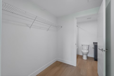 A white toilet sits in a small room with a white wall and a door.