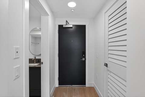 A black refrigerator in a white hallway.