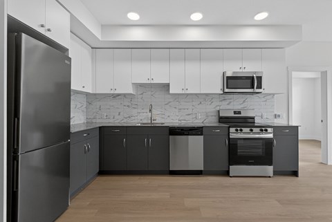 A modern kitchen with a refrigerator, oven, and microwave.