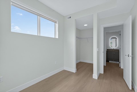 A room with a large window and a door leading to another room.