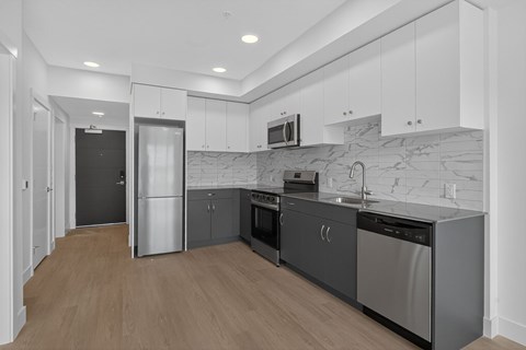 A modern kitchen with stainless steel appliances and wooden flooring.