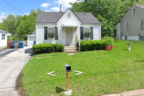 a small white house with a mailbox in the front yard