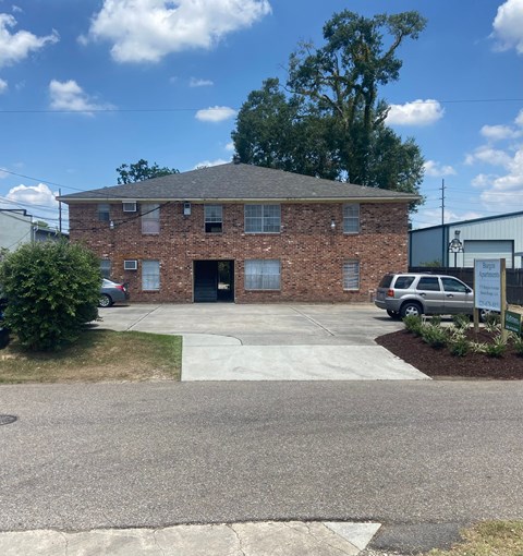 A brick building with a grey car in front.