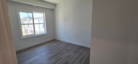 A room with a window and wooden flooring.