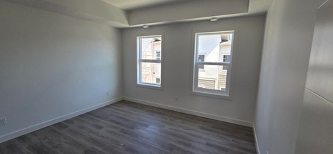 A room with two windows and a grey floor.