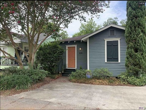 a blue house with a brown door and a driveway