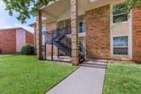 the front of a brick building with stairs and a sidewalk