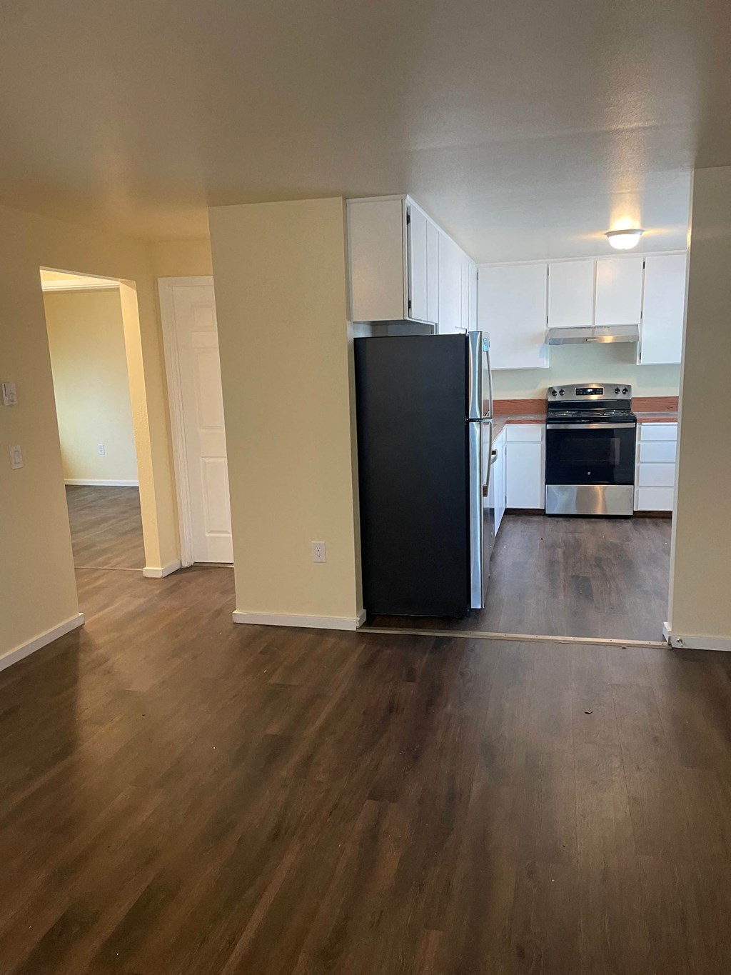A black refrigerator in a kitchen with wooden floors.