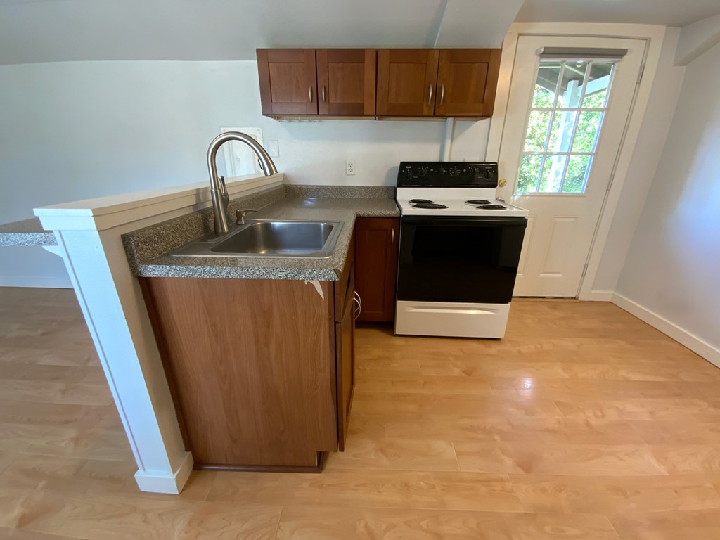 A kitchen with a sink, stove, and cabinets.