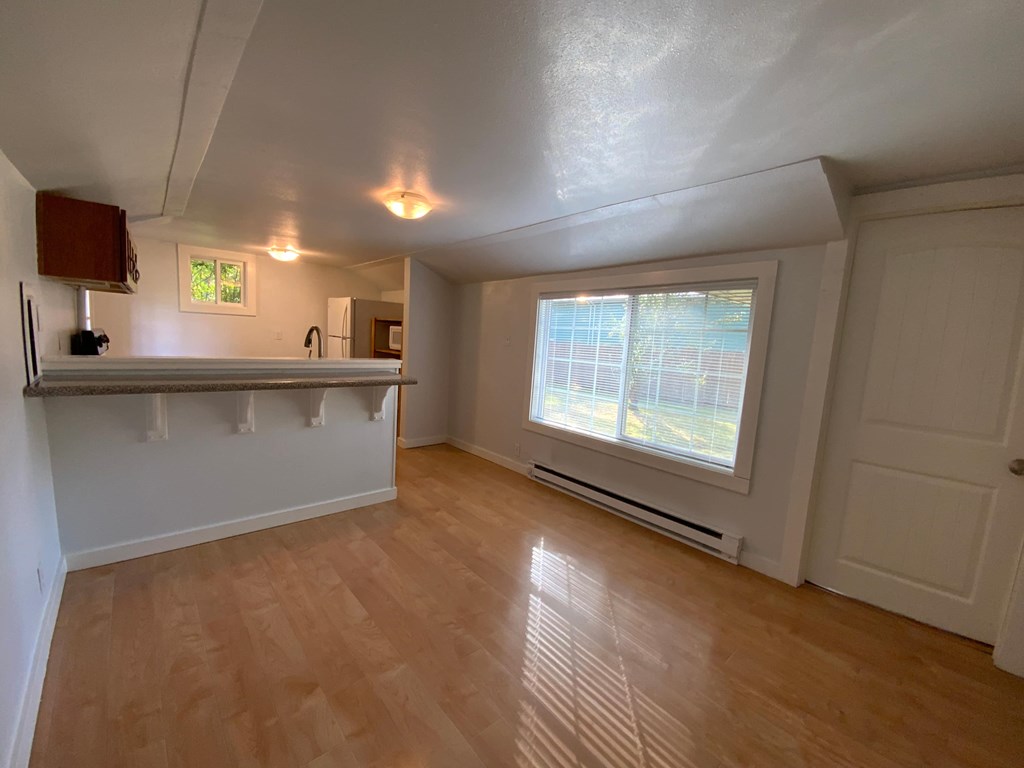 A room with wooden flooring and a window with blinds.
