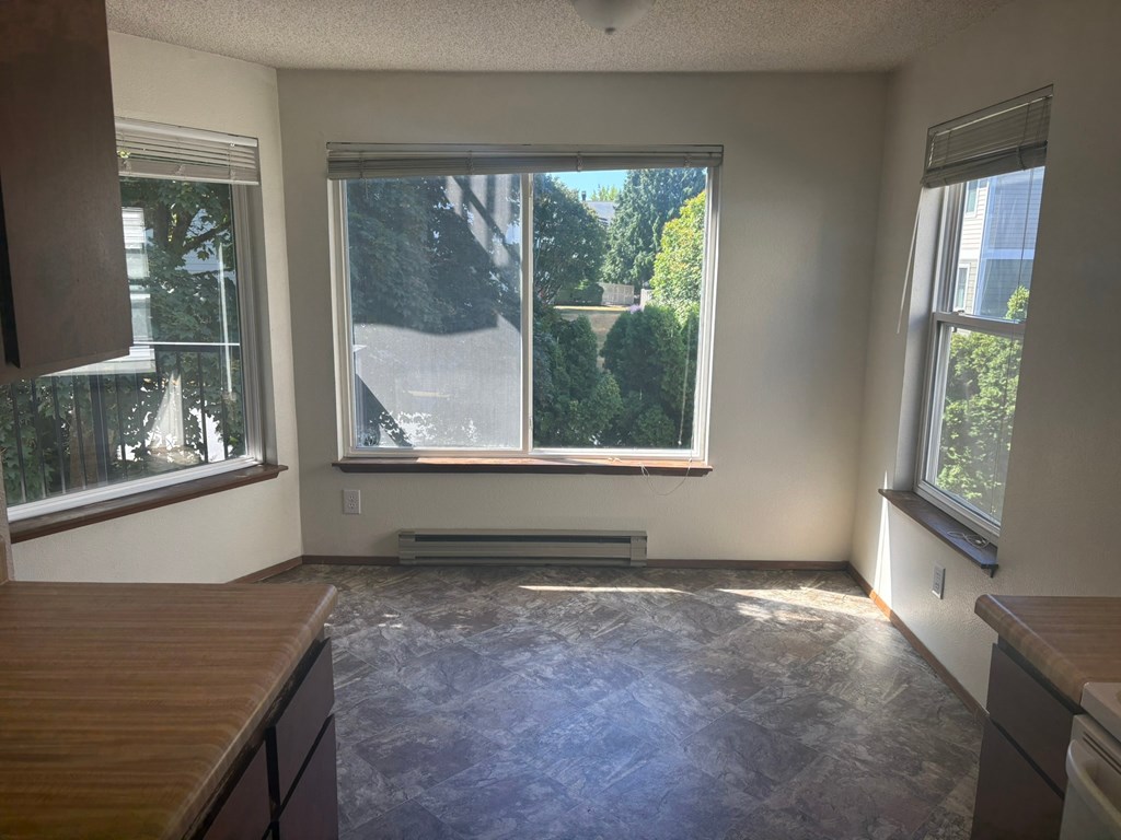 A room with a large window and a view of trees and a building outside.