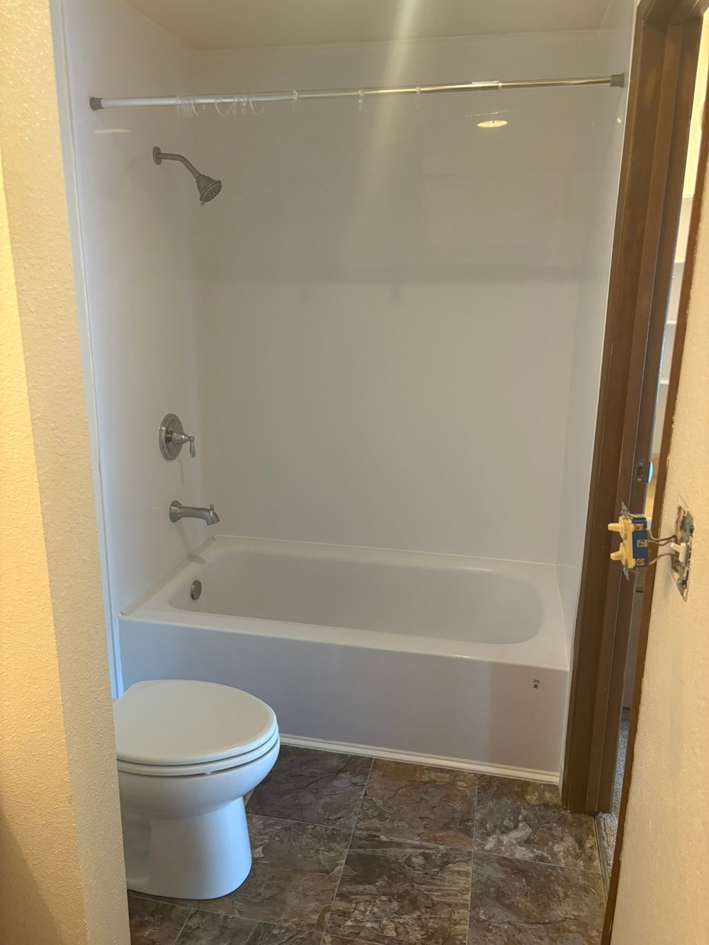 A white toilet sits in a bathroom next to a bathtub.