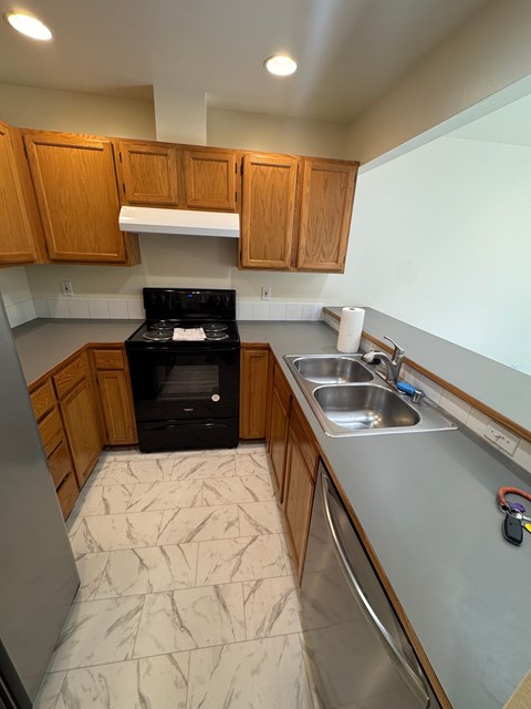 A kitchen with a black stove top oven and wooden cabinets.