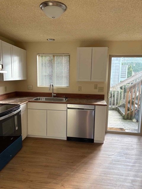A kitchen with white cabinets and a stainless steel sink.