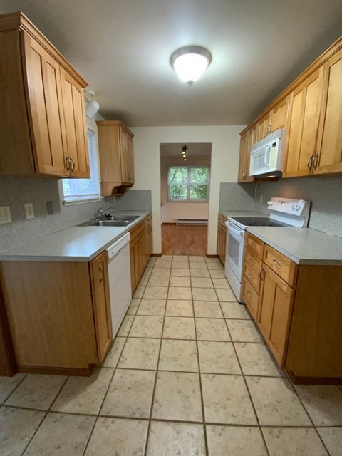 A kitchen with wooden cabinets and a tiled floor.