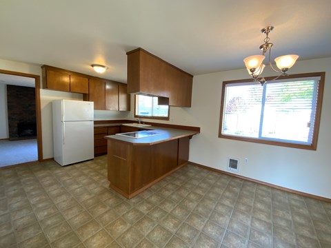 A kitchen with a white refrigerator and wooden cabinets.