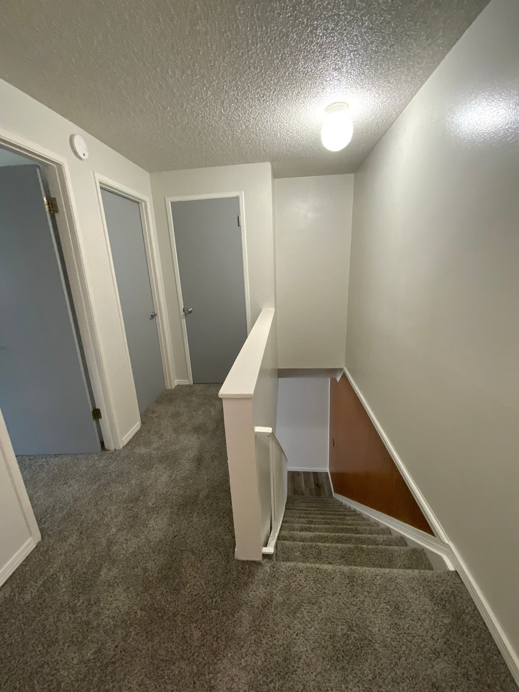 an empty room with a carpeted floor and a stairwell with a white door