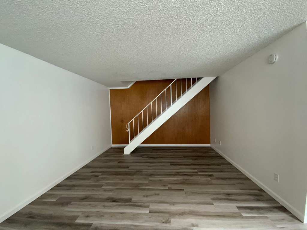 an empty room with a staircase and a wooden floor