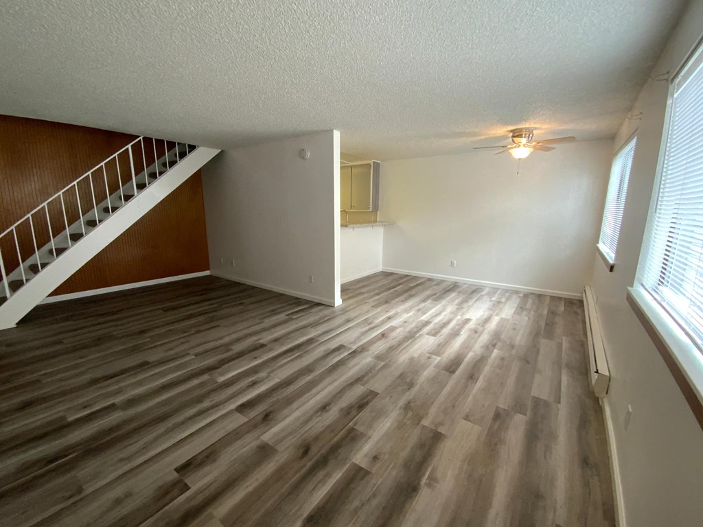 an empty living room with wood flooring and a staircase