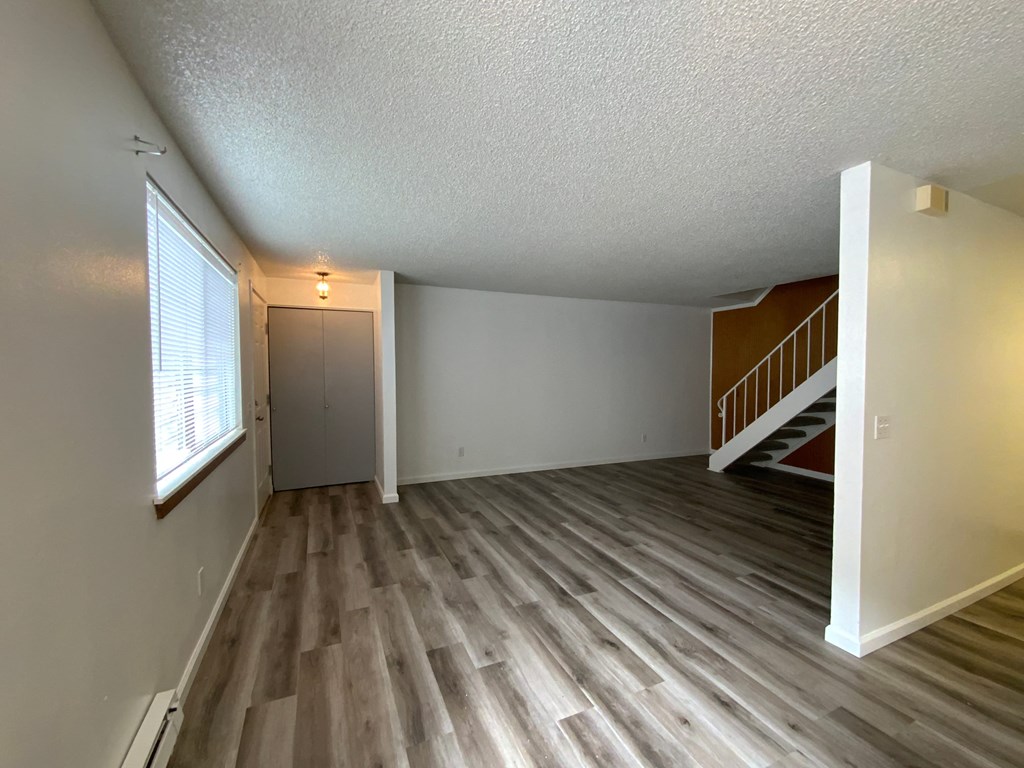 the spacious living room and dining room of an empty house