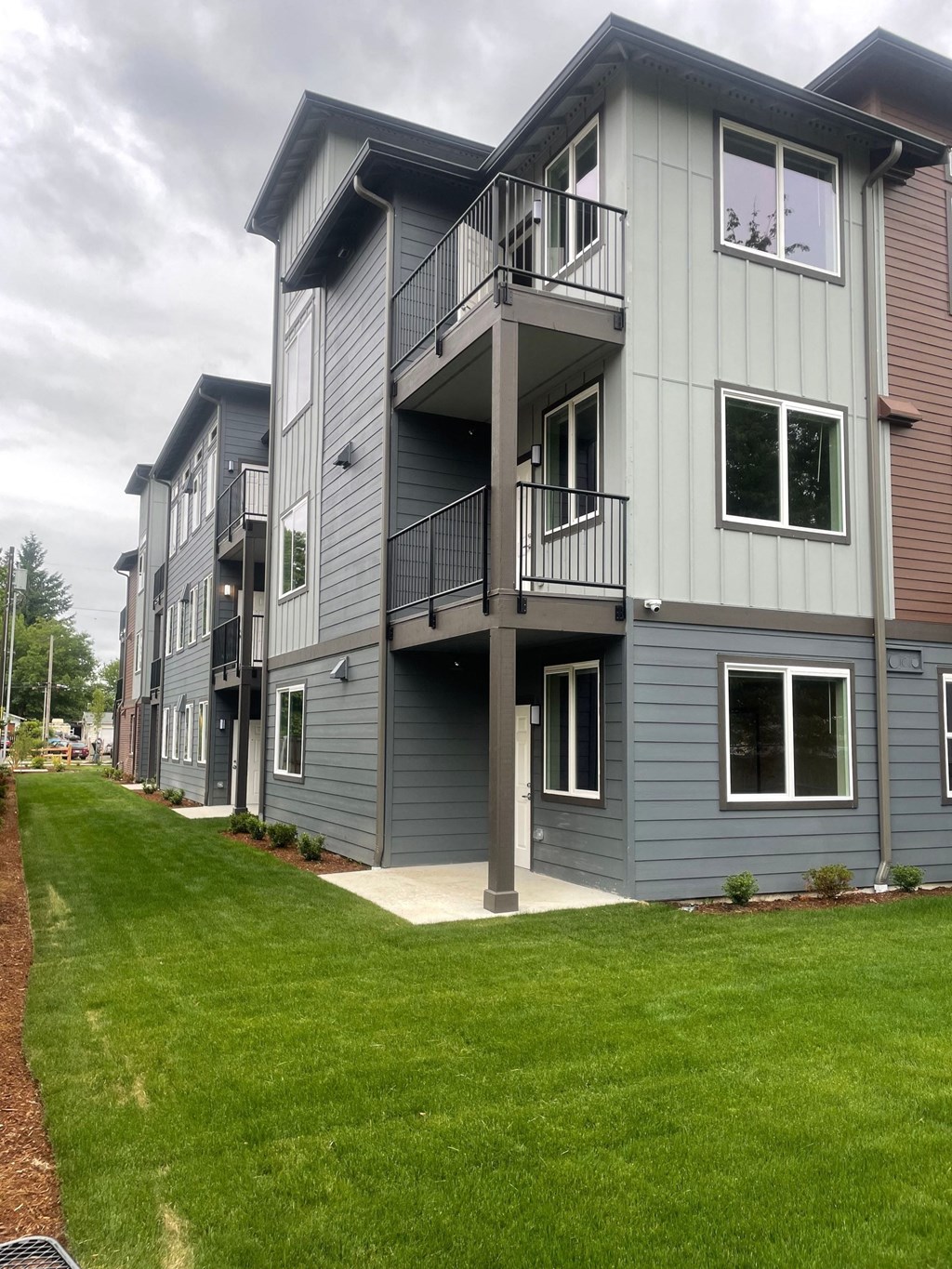 a row of town homes with balconies and a green lawn