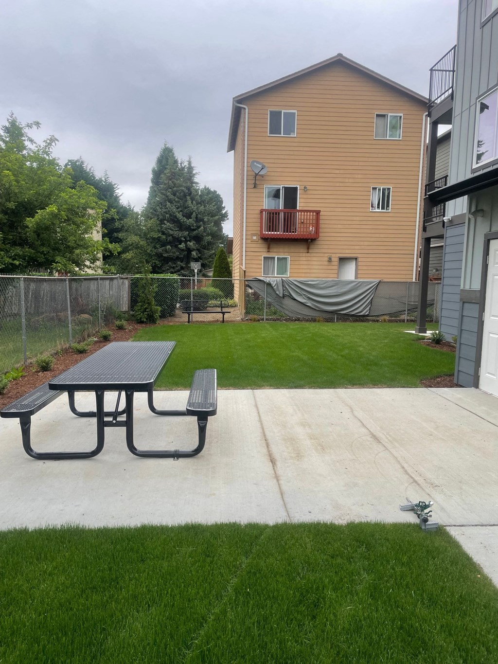 a backyard with a picnic table and a fence and an apartment building