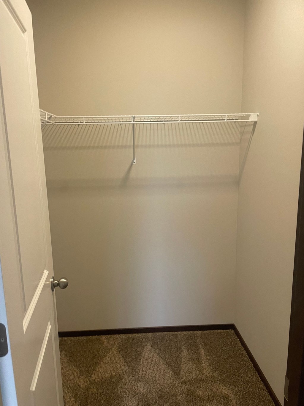 a walk in closet with a white shelf and a door
