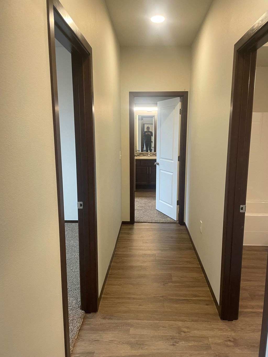 a hallway with a hard wood floor and a door to a bedroom and a bathroom