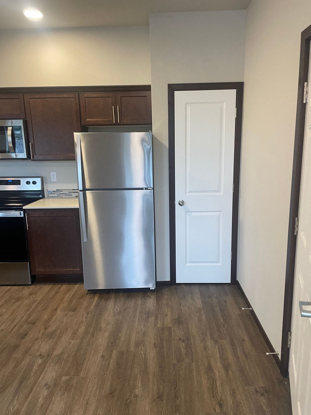 a kitchen with a stainless steel refrigerator and wooden floors