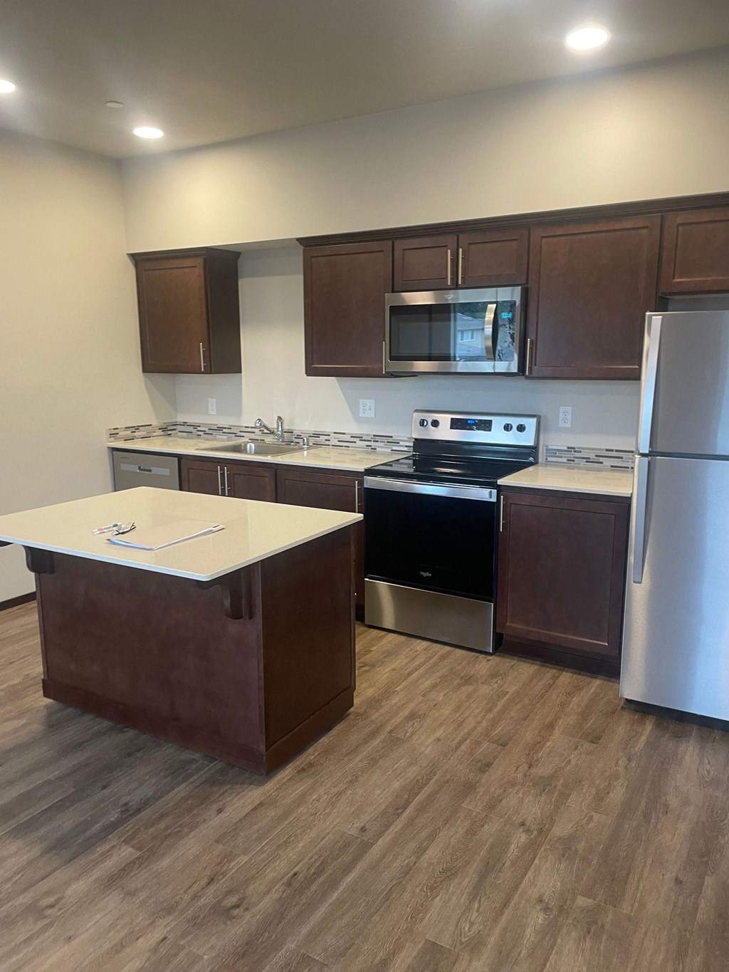 an empty kitchen with stainless steel appliances and wooden floors