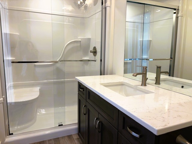 A bathroom with a white sink and a glass shower stall.