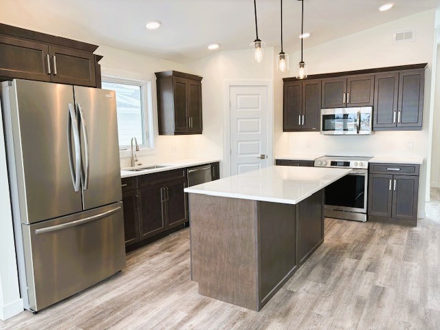 A modern kitchen with a stainless steel refrigerator and dark brown cabinets.