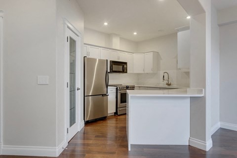 a kitchen with white cabinets and a stainless steel refrigerator