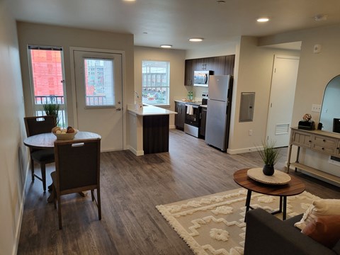 A living room with a couch, a dining table, and a kitchen area in the background.