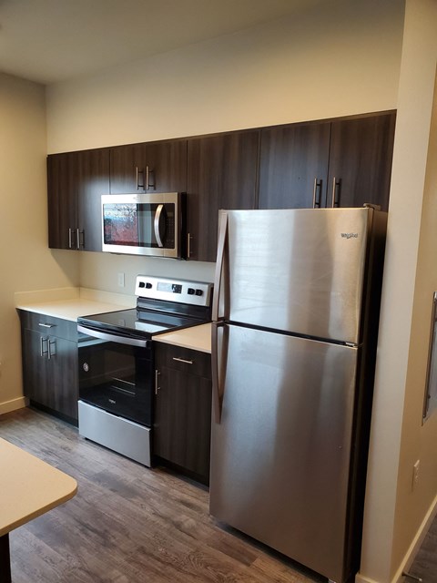 A kitchen with a stainless steel refrigerator and black cabinets.