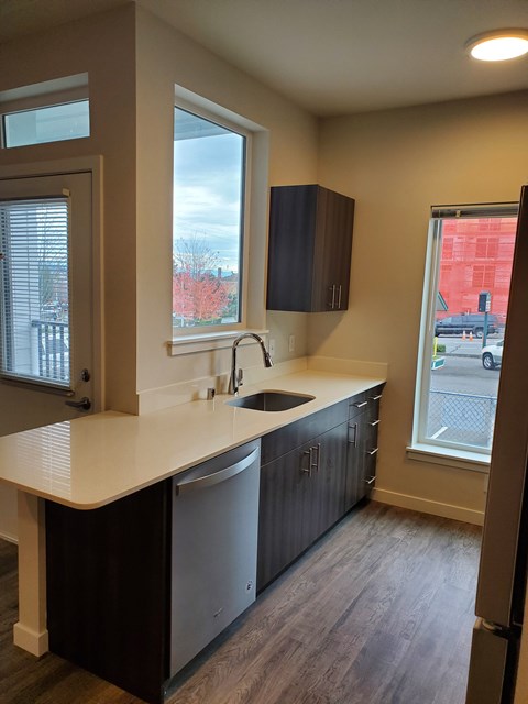A kitchen with a white counter top and dark brown cabinets.