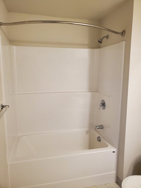 A white bathroom with a tub and toilet.