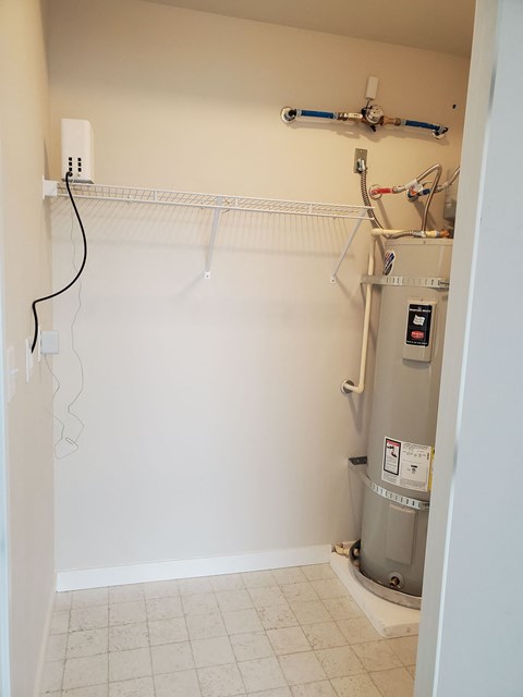 A small room with a water heater and a white wall.