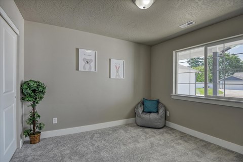 A room with a grey carpet and a grey bean bag chair.