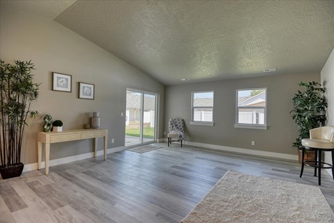 A room with a wooden bench and a chair, a potted plant on the left, and a potted plant on the right.