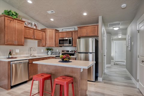A kitchen with a white countertop and red stools.