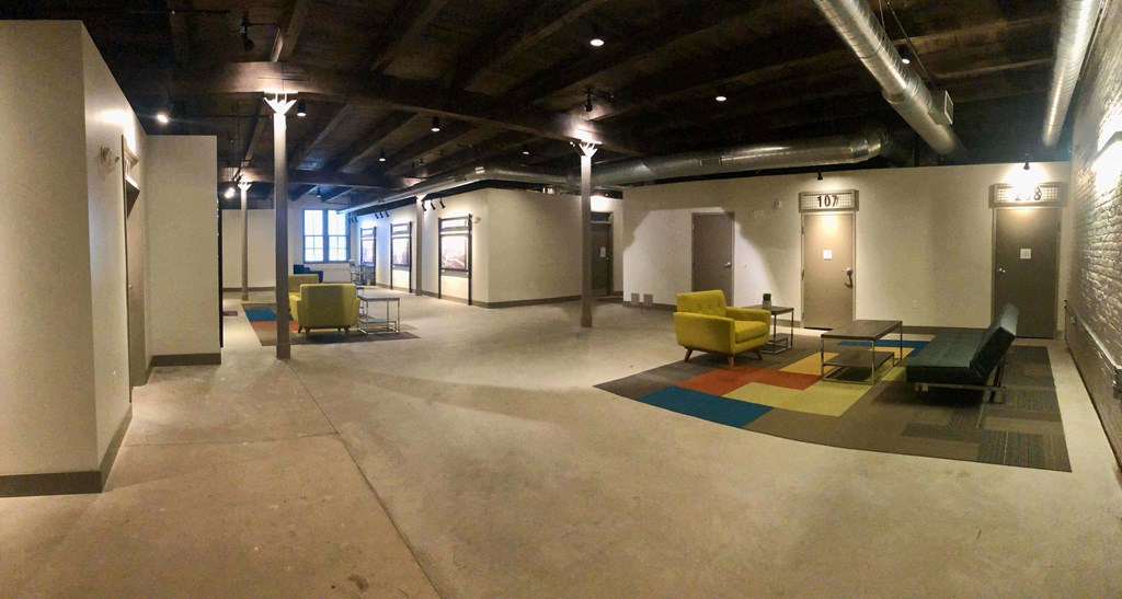 A large open room with a yellow chair and a blue rug.