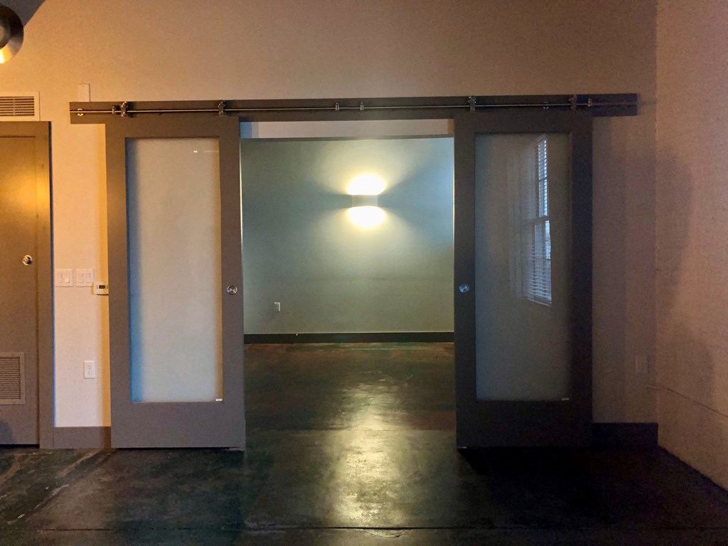 A room with a glass door and a light on the wall.