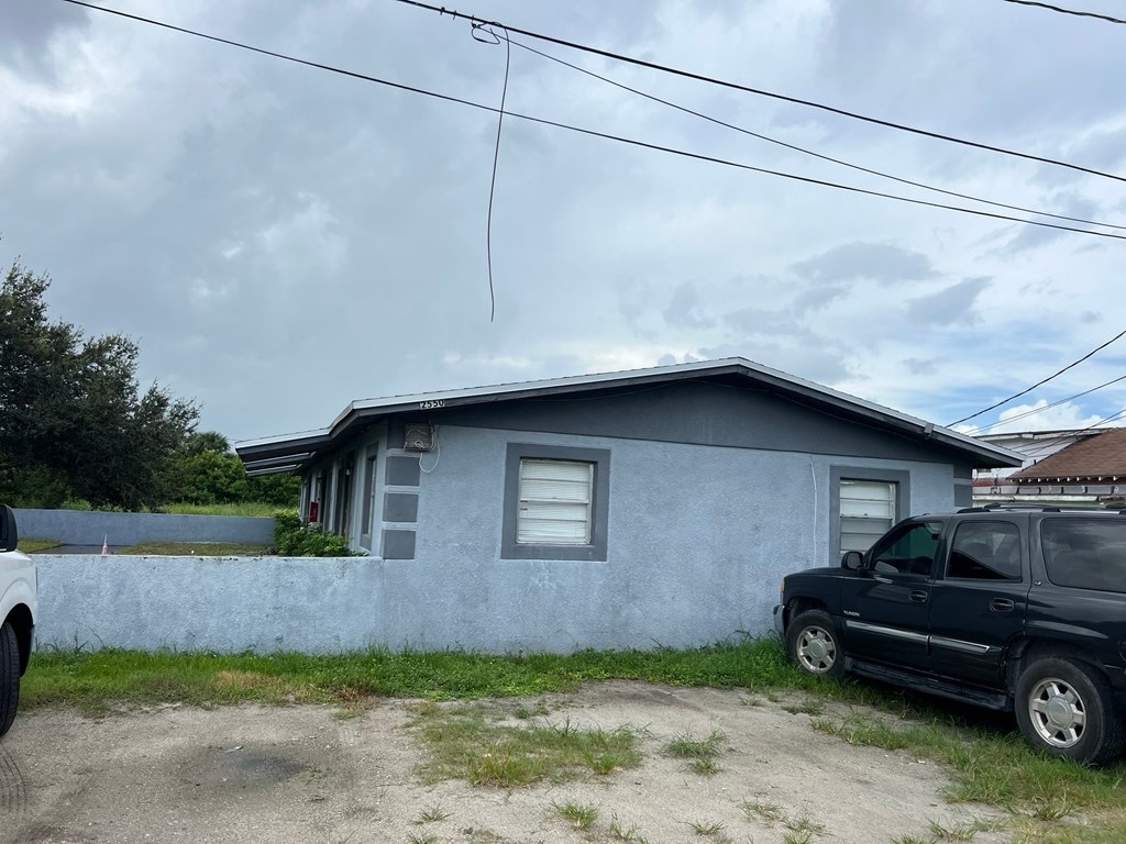 A small blue house with a black car parked in front.