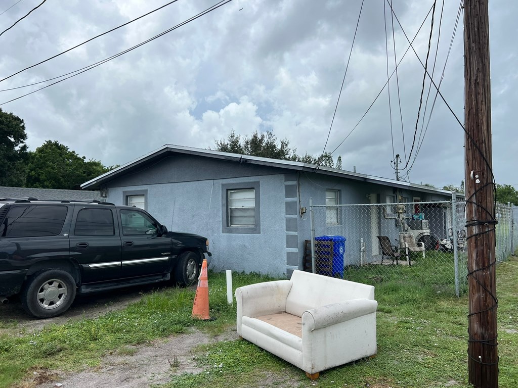 A black truck is parked in front of a blue house with a white couch on the lawn.
